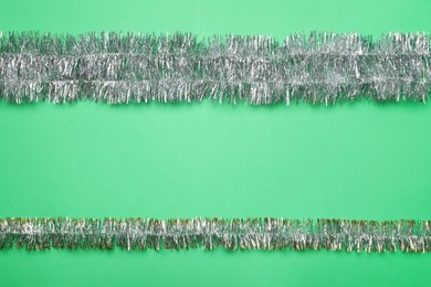 Silver tinsel on green background, flat lay. Space for text