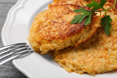 Tasty parsnip cutlets with parsley on grey wooden table, closeup