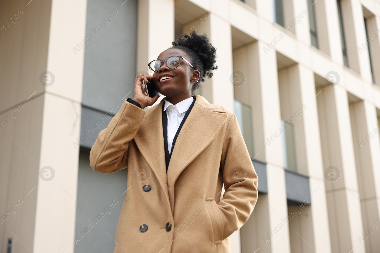 Photo of Happy woman talking on smartphone outdoors, low angle view. Lawyer, businesswoman, accountant or manager