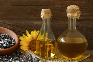 Bottles of sunflower oil, seeds and flower on table