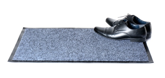 Photo of Black classic shoes on gray doormat against white background