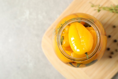 Glass jar with pickled peppers on grey table, flat lay. Space for text