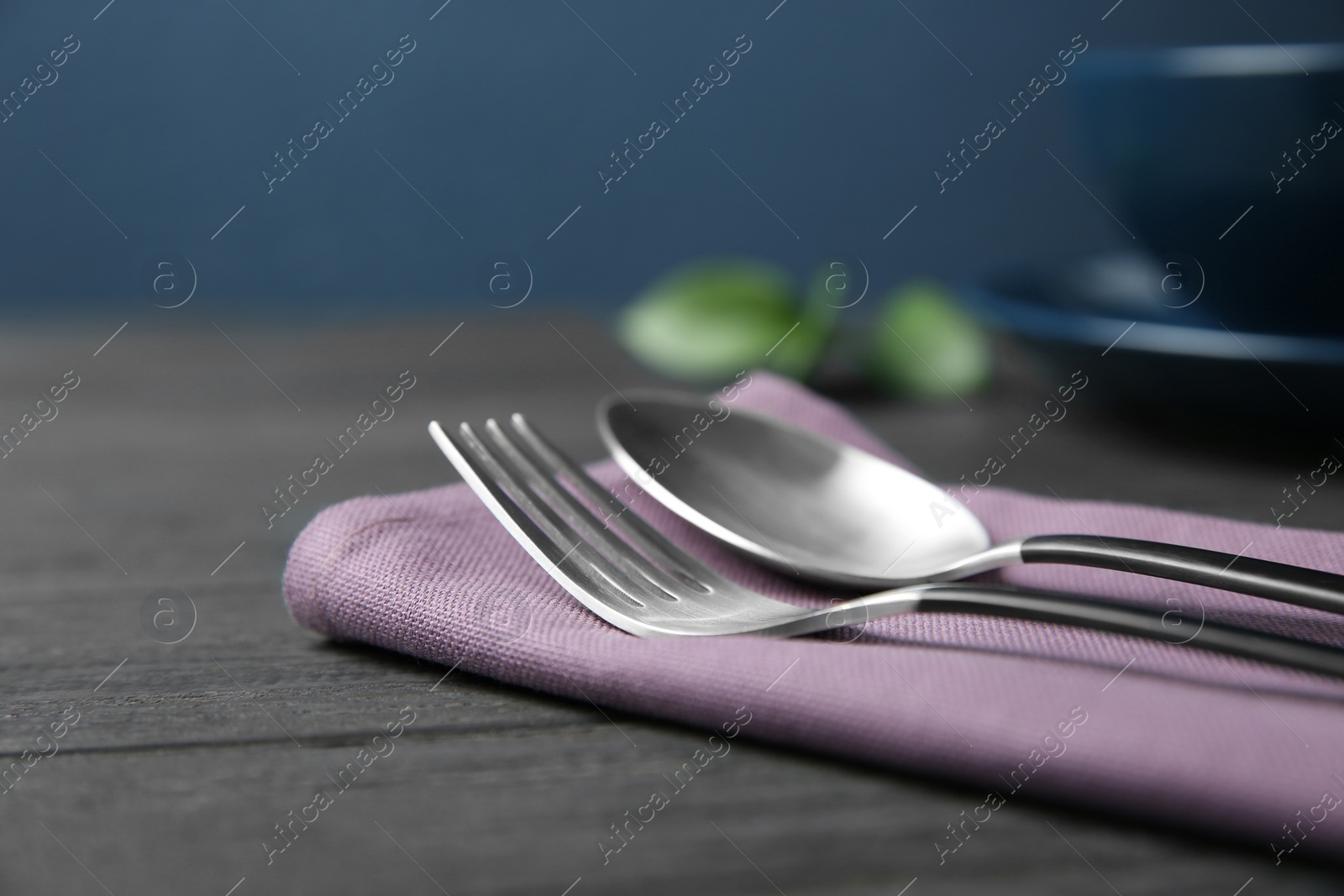 Photo of Cutlery set and dishware on dark wooden table