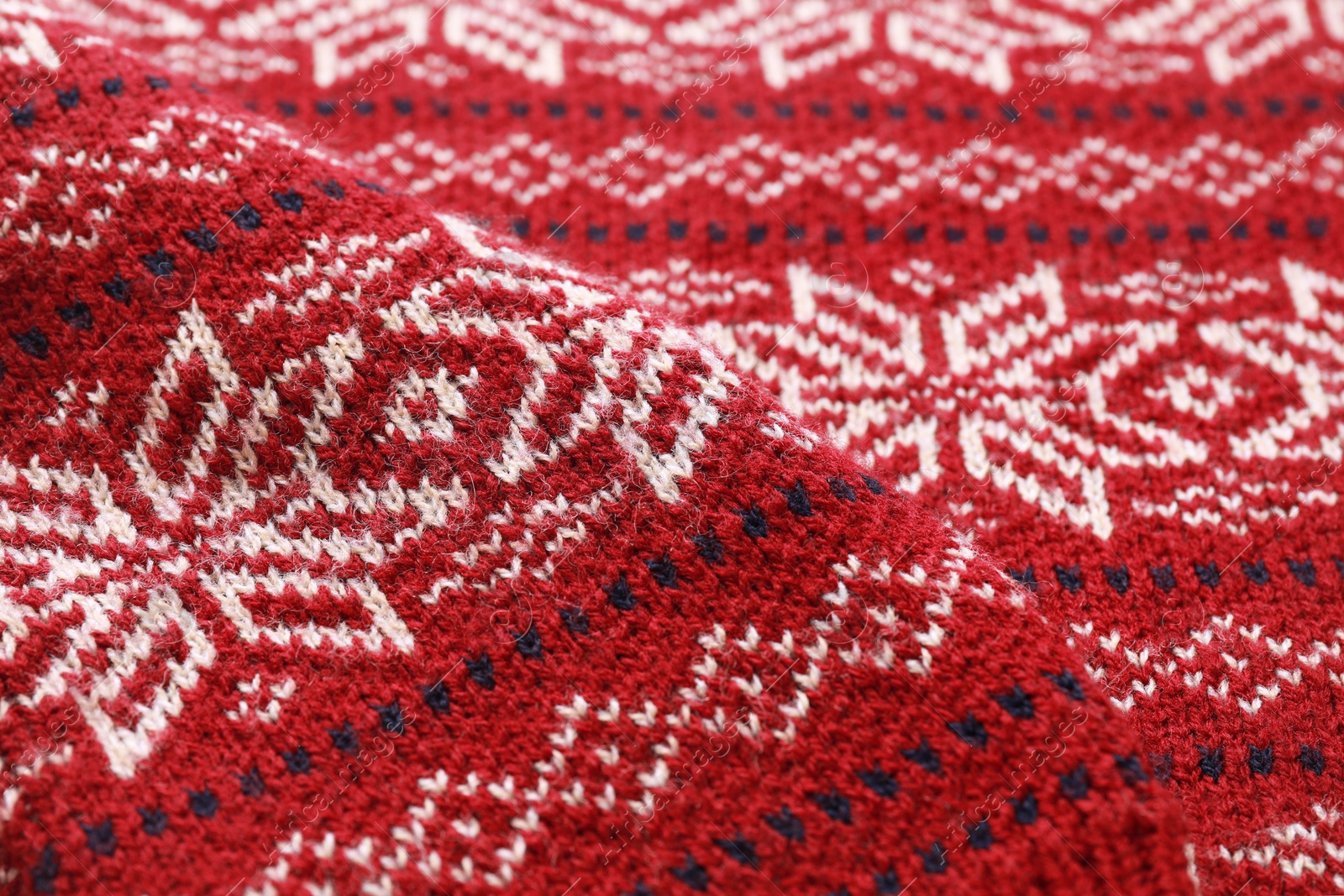 Photo of Warm Christmas sweater with snowflakes as background, closeup