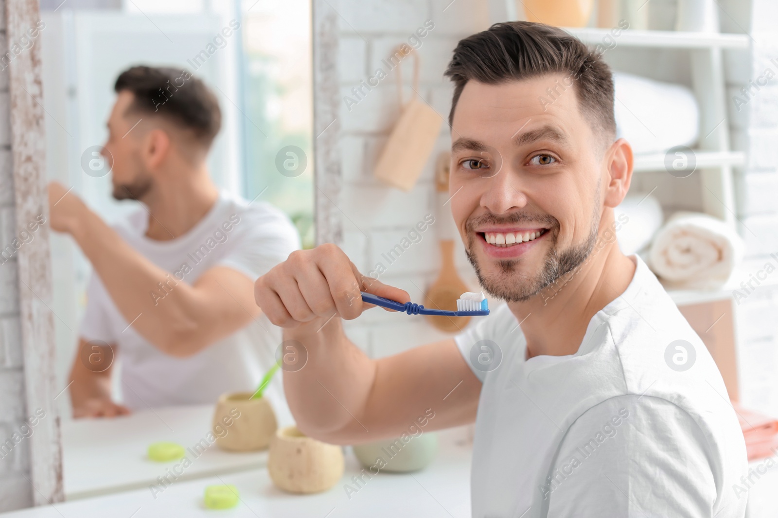 Photo of Young man brushing his teeth in bathroom