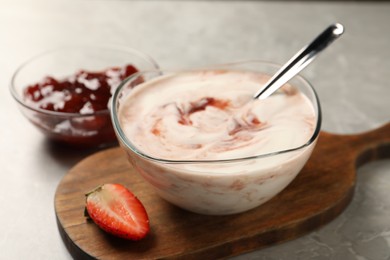 Photo of Tasty yoghurt with jam and strawberry on grey table, closeup