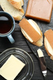 Photo of Tasty sandwiches with quince paste served on black wooden table, flat lay