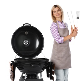 Woman in apron with barbecue grill and utensils on white background