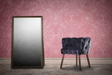 Armchair and mirror near wall with patterned wallpaper. Stylish room interior