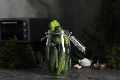 Photo of Pickling jar with fresh cucumbers on dark grey kitchen table