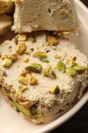 Photo of Pieces of tasty halva with pistachios on table, closeup