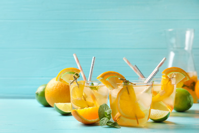 Photo of Delicious refreshing drink with orange and lime slices on light blue wooden table