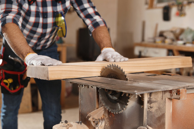 Photo of Professional carpenter working with sawmill machine in workshop, closeup