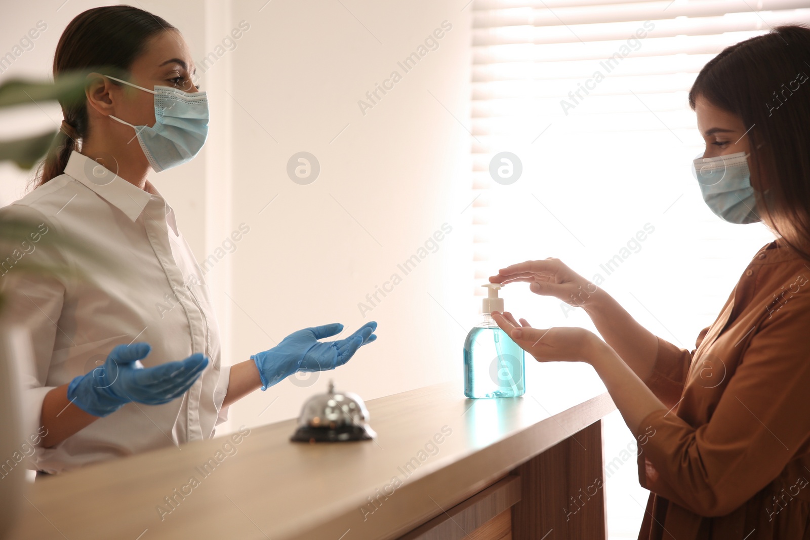 Photo of Woman applying antiseptic gel at hotel reception