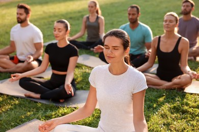 Group of people practicing yoga outdoors on sunny day, selective focus. Lotus pose