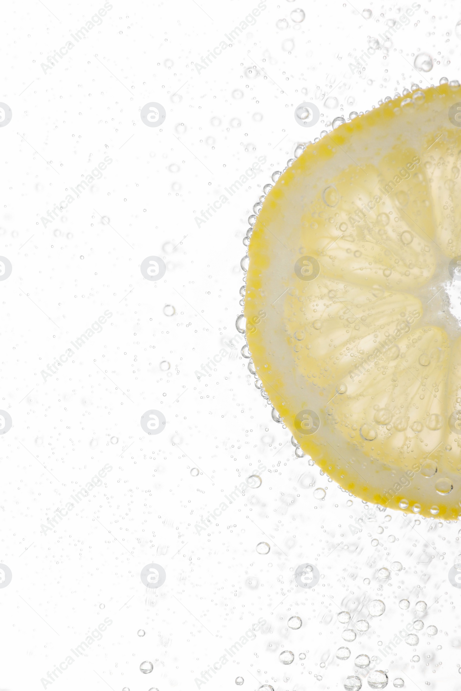 Photo of Juicy lemon slice in soda water against white background, closeup