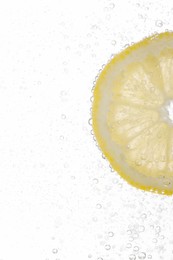 Photo of Juicy lemon slice in soda water against white background, closeup