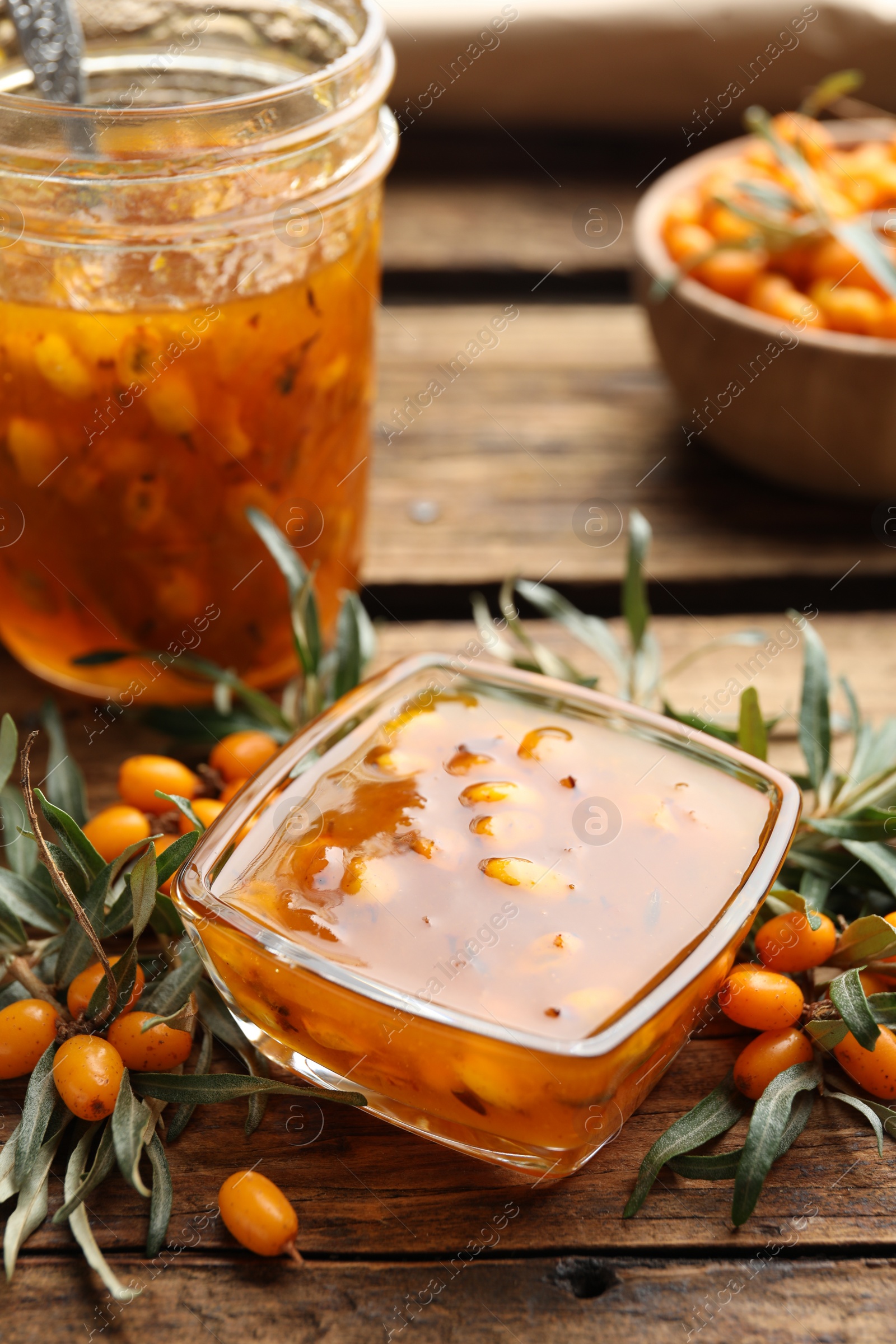 Photo of Delicious sea buckthorn jam and fresh berries on wooden table