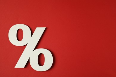 Photo of White percent sign on red background, top view. Space for text