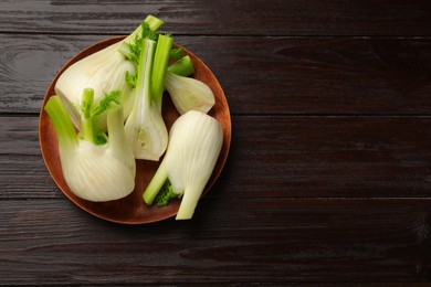 Whole and cut fennel bulbs on wooden table, top view. Space for text