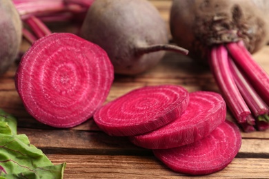 Photo of Cut raw beet on wooden table, closeup