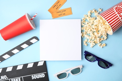 Photo of Flat lay composition with blank paper, popcorn and clapper on color background, mockup for design. Watching cinema