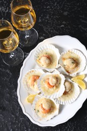 Photo of Fried scallops in shells and wine on black textured table, above view