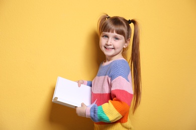 Photo of Cute little girl with book on color background