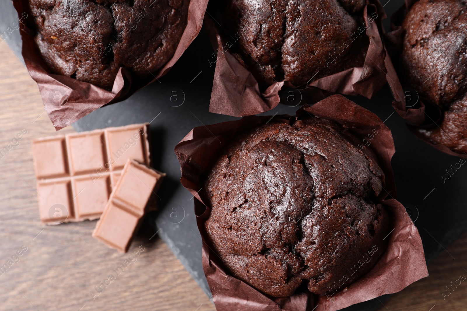 Photo of Tasty chocolate muffins on wooden table, top view