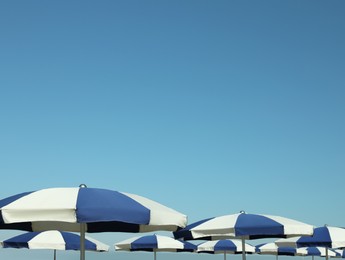 Photo of Many blue and white beach umbrellas near sea