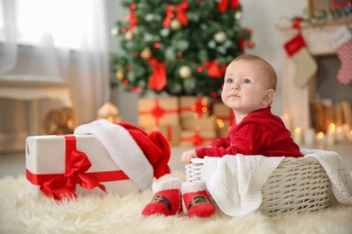 Photo of Cute baby sitting in basket at home. Christmas celebration