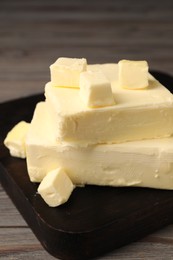 Photo of Pieces of tasty butter on wooden table, closeup