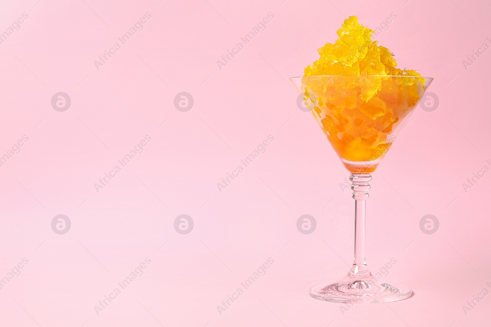 Photo of Shaving ice in martini glass on pink background, space for text