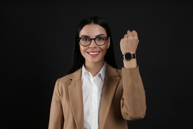 Photo of Businesswoman with wristwatch on black background. Time management