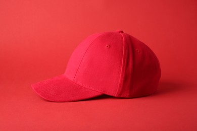 Photo of Stylish red baseball cap on color background