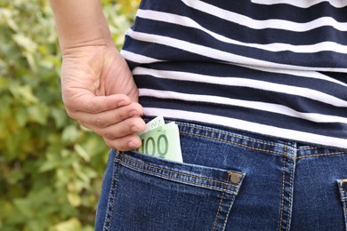 Man putting money into pocket of jeans outdoors, closeup