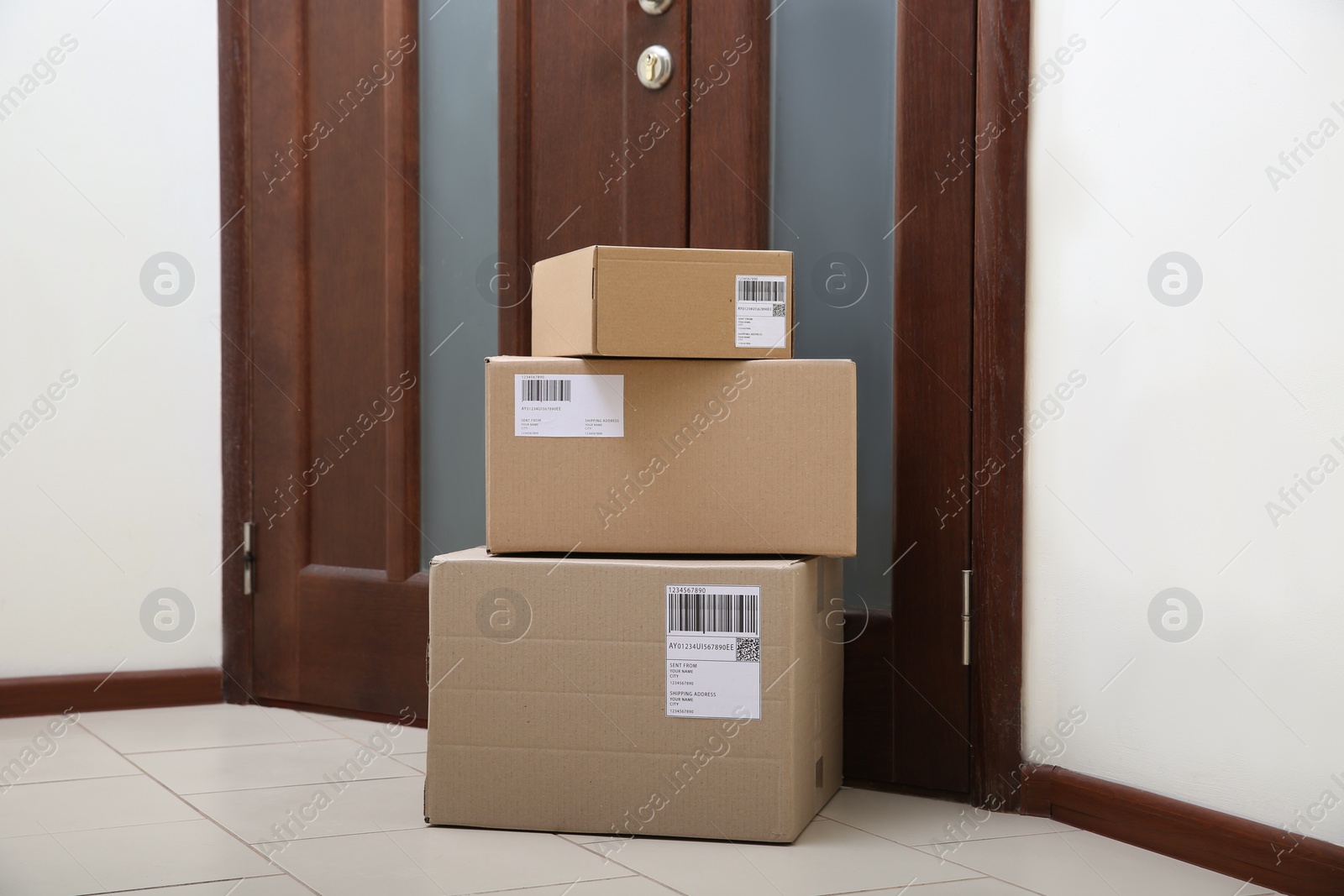 Photo of Stacked parcels near door on floor. Delivery service