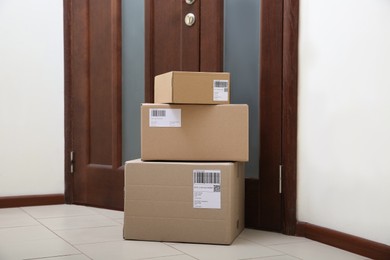 Photo of Stacked parcels near door on floor. Delivery service