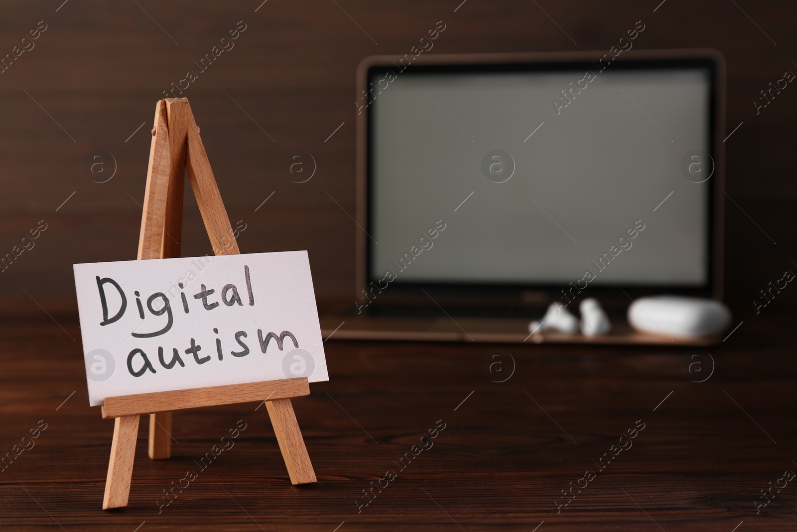 Photo of Card with phrase Digital Autism and laptop on wooden table, selective focus