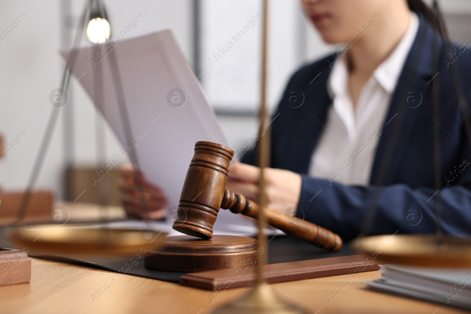 Photo of Notary reading document at table in office, focus on gavel