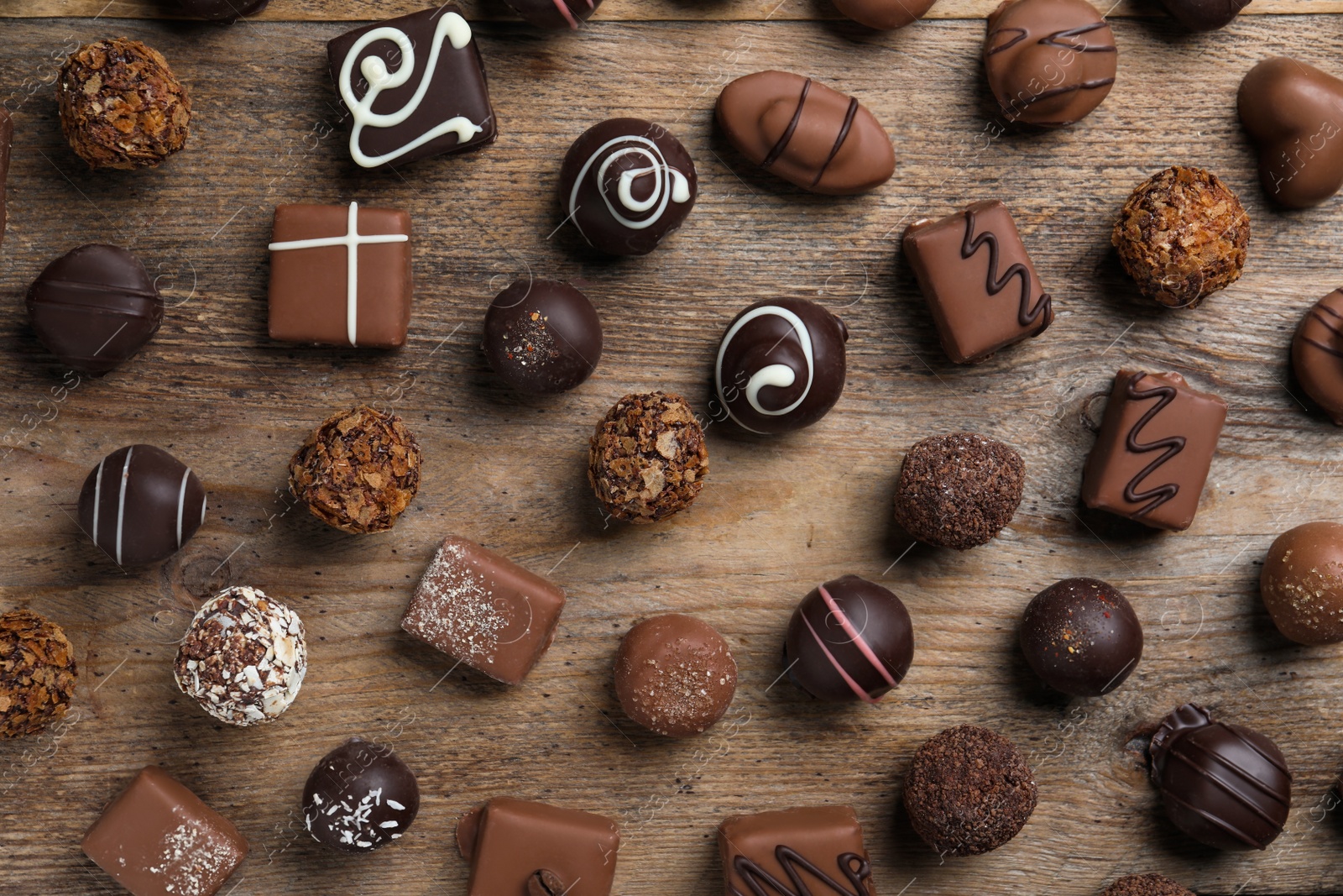 Photo of Different delicious chocolate candies on wooden table, flat lay