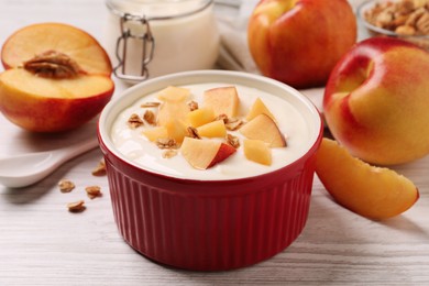 Photo of Delicious yogurt with fresh peach and granola on white wooden table