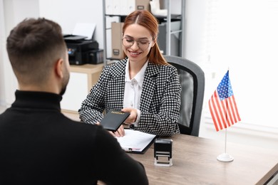 Immigration to United States of America. Smiling embassy worker giving passport to man in office