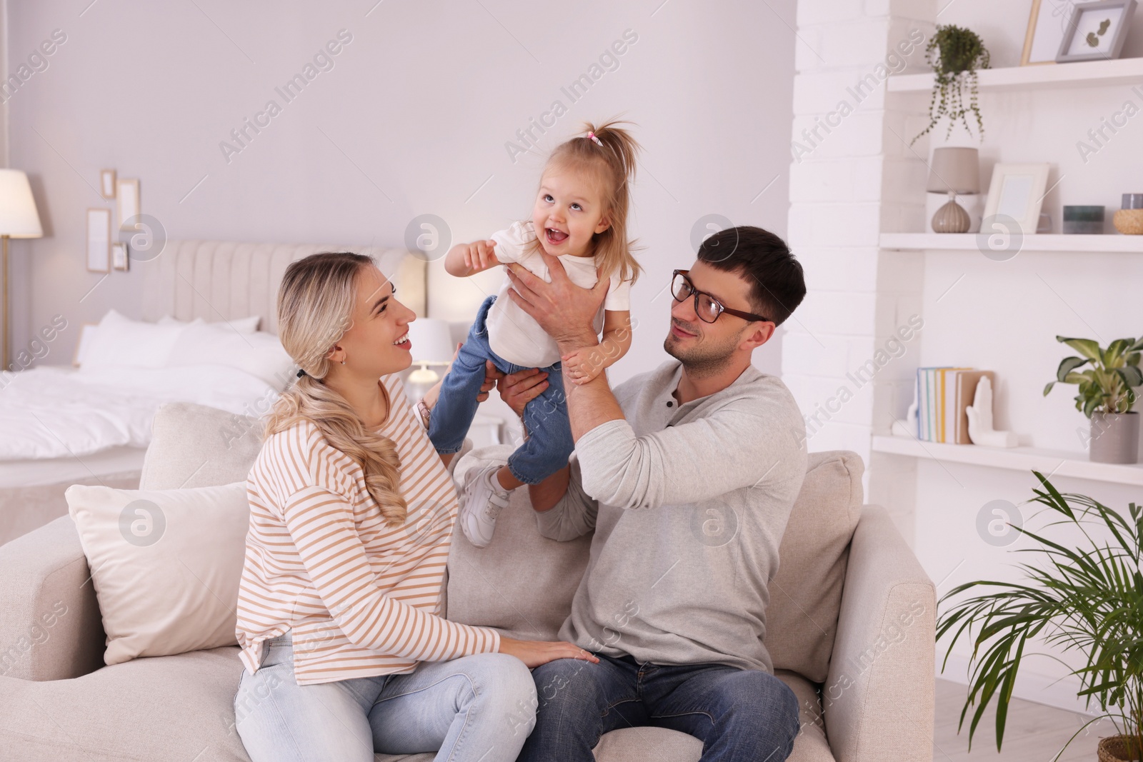 Photo of Family with little daughter spending time together on sofa at home