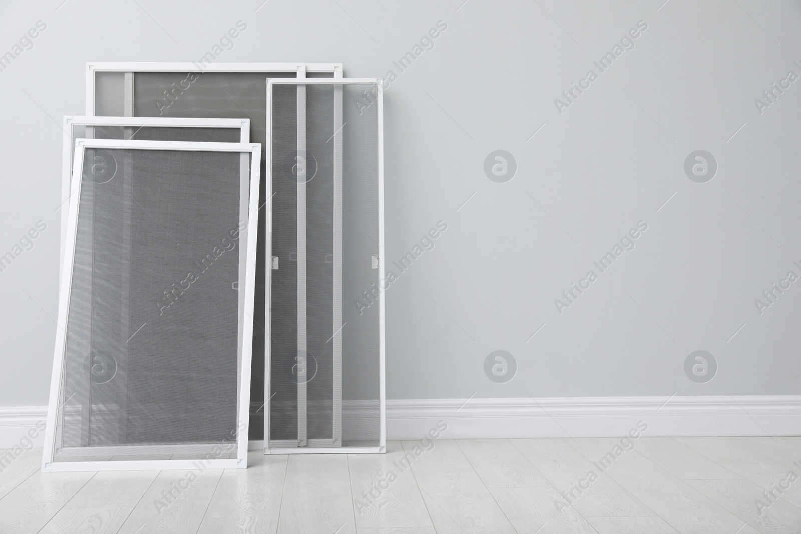 Photo of Set of window screens near light grey wall indoors. Space for text
