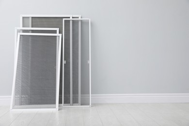 Photo of Set of window screens near light grey wall indoors. Space for text