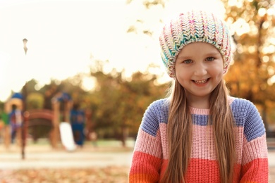 Photo of Cute little girl with knitted hat in park. Autumn walk
