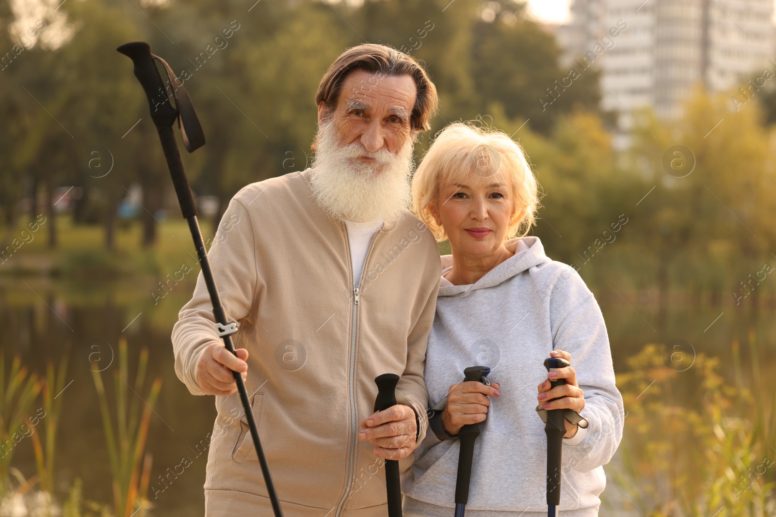 Photo of Senior man and woman with Nordic walking poles outdoors