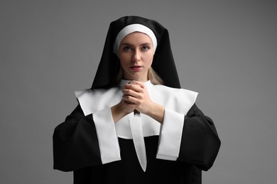 Photo of Woman in nun habit holding knife on grey background