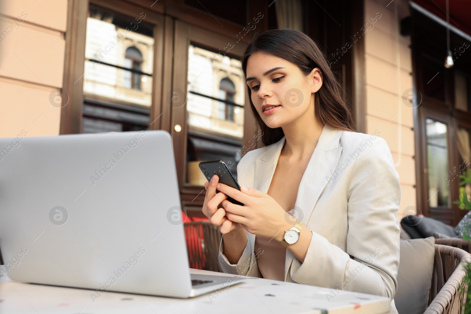 Photo of Beautiful young woman using smartphone in outdoor cafe